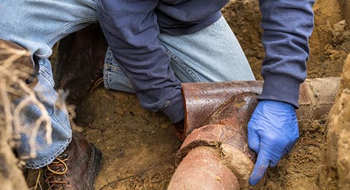Clogged sewer drain causing backup in a Calgary home, showing water overflowing from a sink and professional plumber tools nearby