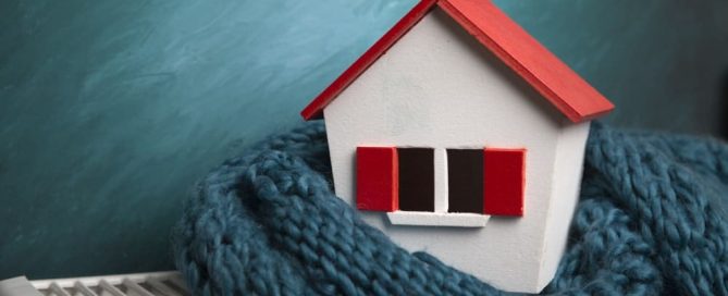 High efficiency furnaces in Calgary Alberta portrayed by small house wrapped in scarf on an electric heater