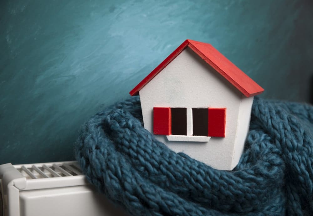 High efficiency furnaces in Calgary Alberta portrayed by small house wrapped in scarf on an electric heater